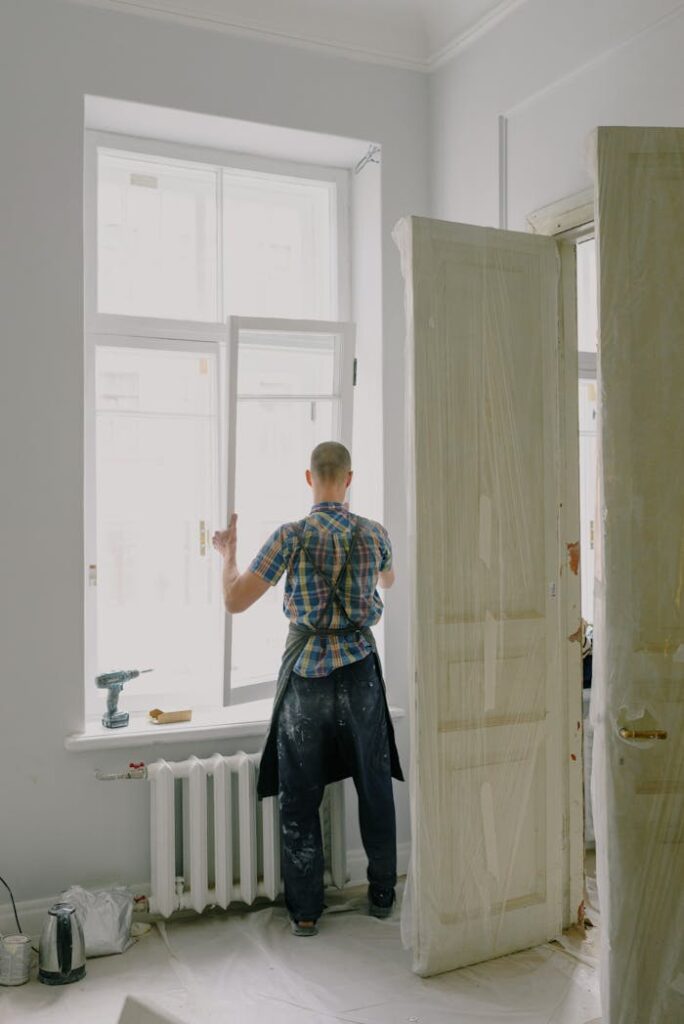 Faceless handyman mounting window in new house